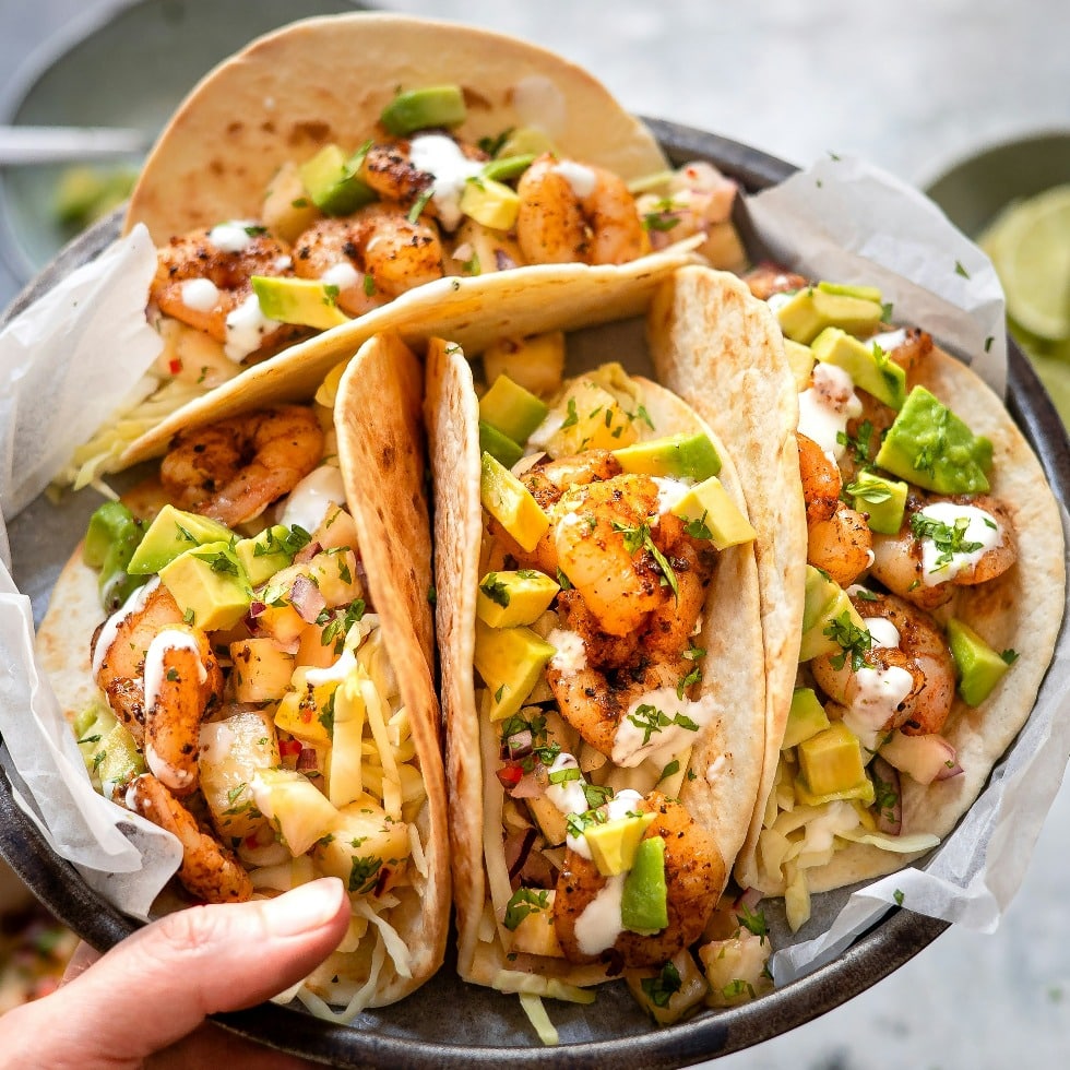 A Hand Holding a Plate of Tacos